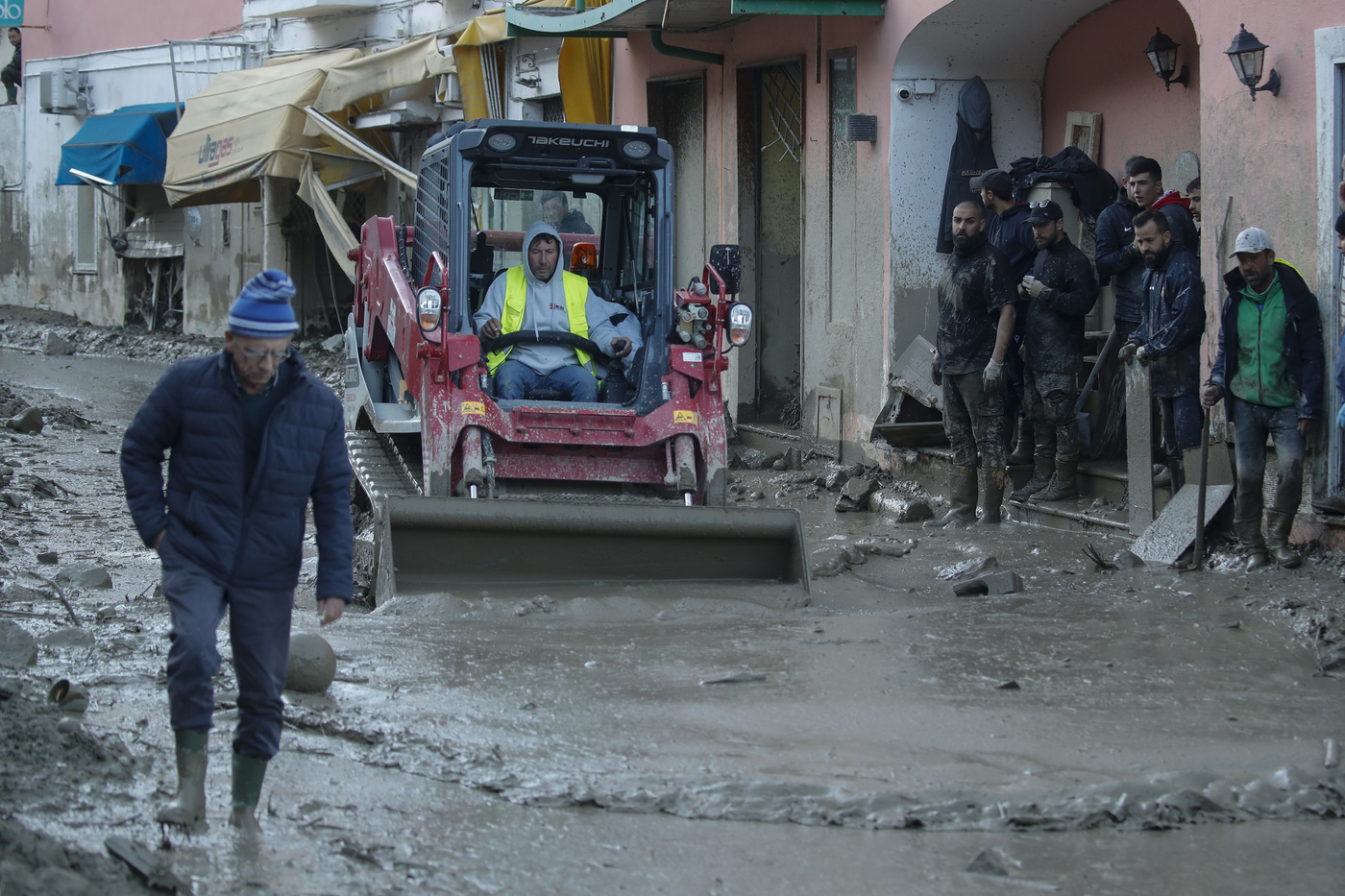 Workers clear mud and debris from a street after heavy rainfall triggered landslides that collapsed buildings and left as many as 12 people missing, in Casamicciola, on the southern Italian island of Ischia, Sunday, Nov. 27, 2022. Authorities said that the landslide that early Saturday destroyed buildings and swept parked cars into the sea left one person dead and 12 missing. (AP Photo/Salvatore Laporta)