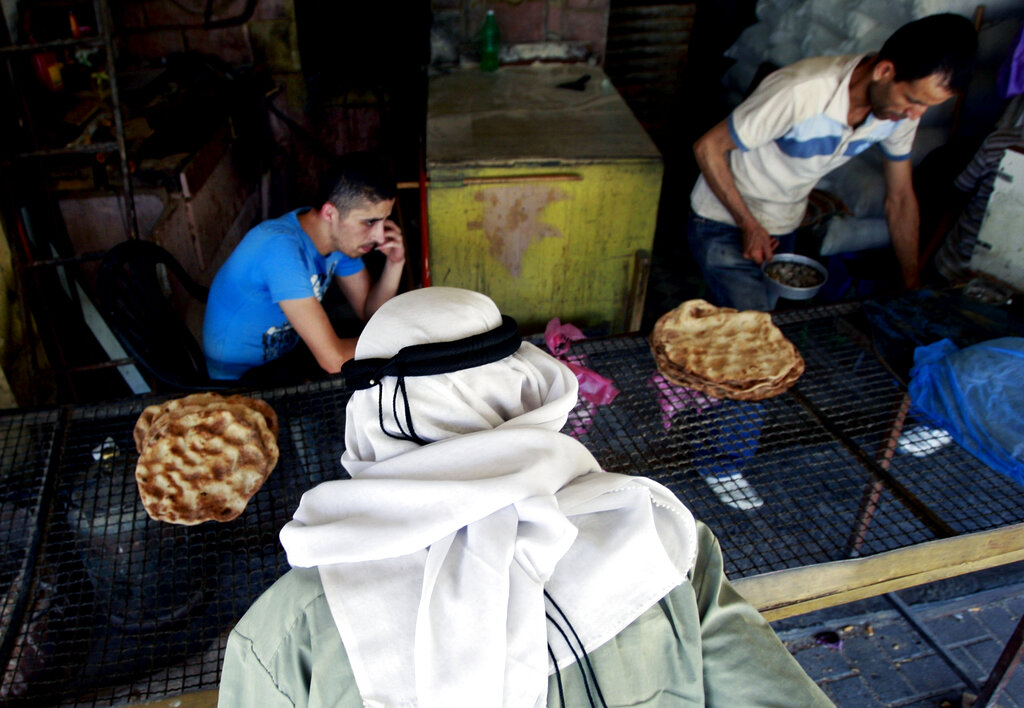 A Palestinian man buys traditional bread at a popular bakery in the West Bank city of Jenin, Thursday, June 26, 2014. (AP Photo/Mohammed Ballas)