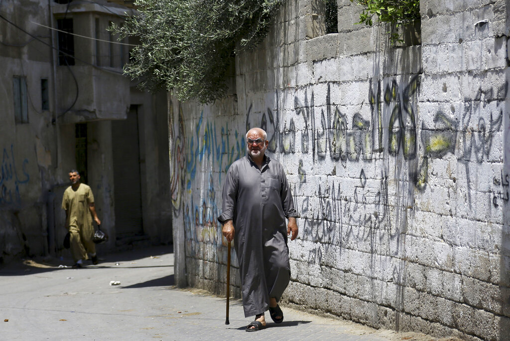 A Palestinian man walks past graffiti of Islamic Jihad in Khan Younis, the southern Gaza Strip, Friday, May 9, 2014. Arabic reads, 