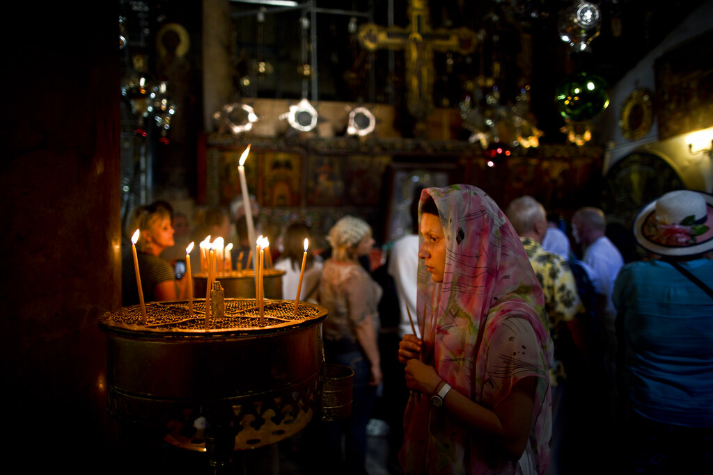 A Christian worshipper prays before lighting a candle inside the Church of Nativity, believed by many to be the birthplace of Jesus Christ, in the West Bank city of Bethlehem, Tuesday, June 24, 2014. (AP Photo/Muhammed Muheisen)