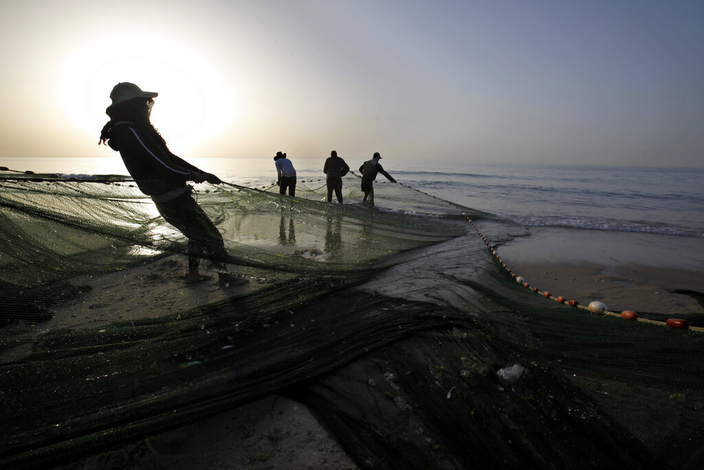 Palestinian fishermen pull in their nets from the waters of the Mediterranean Sea during sunset at the beach in Gaza City, Monday, March 11, 2013.  Israel imposes a maritime blockade of the Gaza Strip, restricting access by Palestinian fishermen to 10 miles from shore for fishing, but often the boats are challenged before they reach that limit. (AP Photo/Adel Hana)