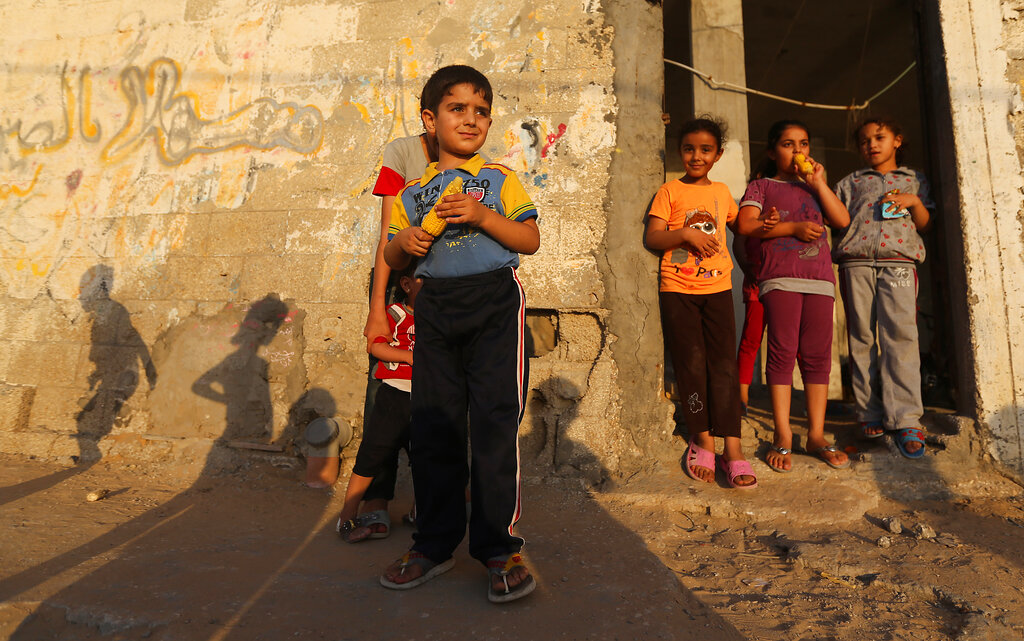 Palestinian children stand near their house eating corn at the Shati refugee camp, in Gaza City, Wednesday, June 18, 2014. Al- Shati refugee camp, a Palestinian refugee camp located in the northern Gaza Strip along the Mediterranean Sea coastline in the Gaza Governorate, and more specifically Gaza City. The camp is the third largest refugee camp in the Palestinian Territories. (AP Photo/Hatem Moussa)
