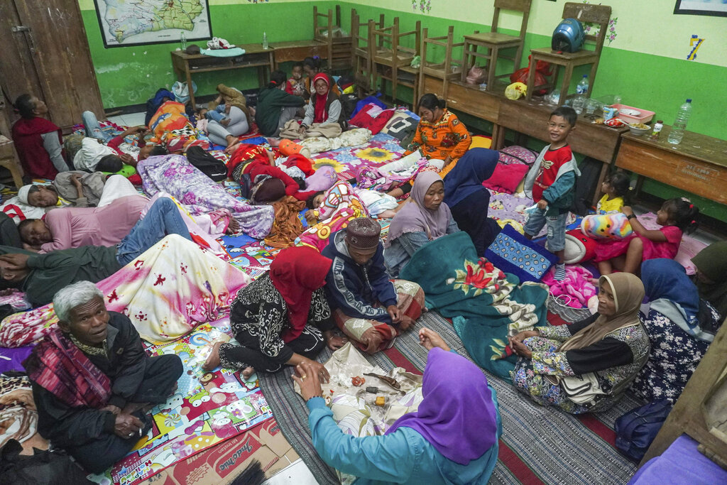 People rest at a school turned into temporary shelter for those evacuated from their homes following the eruption of Mount Semeru, in Lumajang, East Java, Indonesia, Sunday, Dec. 4, 2022. Indonesia's highest volcano on its most densely populated island released searing gas clouds and rivers of lava Sunday in its latest eruption. (AP Photo/Dicky Bisinglasi)
