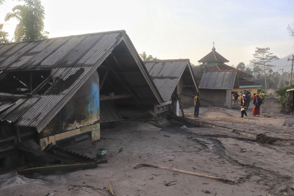 Villagers inspect the damage as houses are seen buried in volcanic ash from the eruption of Mount Semeru in Kajar Kuning village in Lumajang, East Java, Indonesia, Monday, Dec. 5, 2022. Indonesia's highest volcano on its most densely populated island released searing gas clouds and rivers of lava Sunday in its latest eruption. (AP Photo/Imanuel Yoga)