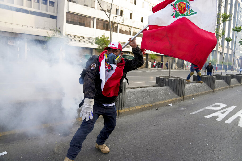 A supporter of ousted President Pedro Castillo waves a Peru's flag during a protest in Lima, Peru, Monday, Dec. 12, 2022. Peru's Congress voted to remove Castillo from office Wednesday and replace him with the vice president, shortly after Castillo tried to dissolve the legislature ahead of a scheduled vote to remove him. (AP Photo/Martin Mejia)