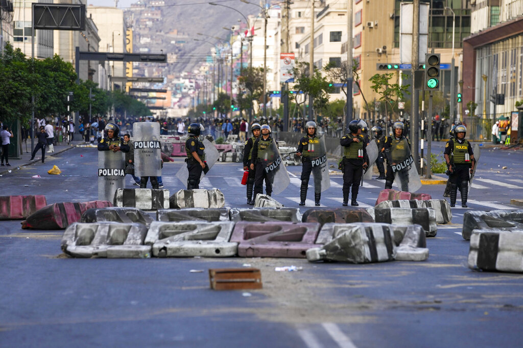 Police stand guard at a barricade as supporters of ousted President Pedro Castillo protest in Lima, Peru, Monday, Dec. 12, 2022. Peru's Congress voted to remove Castillo from office Wednesday and replace him with the vice president, shortly after Castillo tried to dissolve the legislature ahead of a scheduled vote to remove him. (AP Photo/Martin Mejia)
