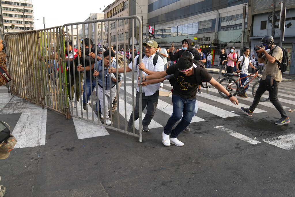Supporters of ousted President Pedro Castillo carry a fence to make a barricade during a protest in Lima, Peru, Monday, Dec. 12, 2022. Peru's Congress voted to remove Castillo from office Wednesday and replace him with the vice president, shortly after Castillo tried to dissolve the legislature ahead of a scheduled vote to remove him. (AP Photo/Martin Mejia)