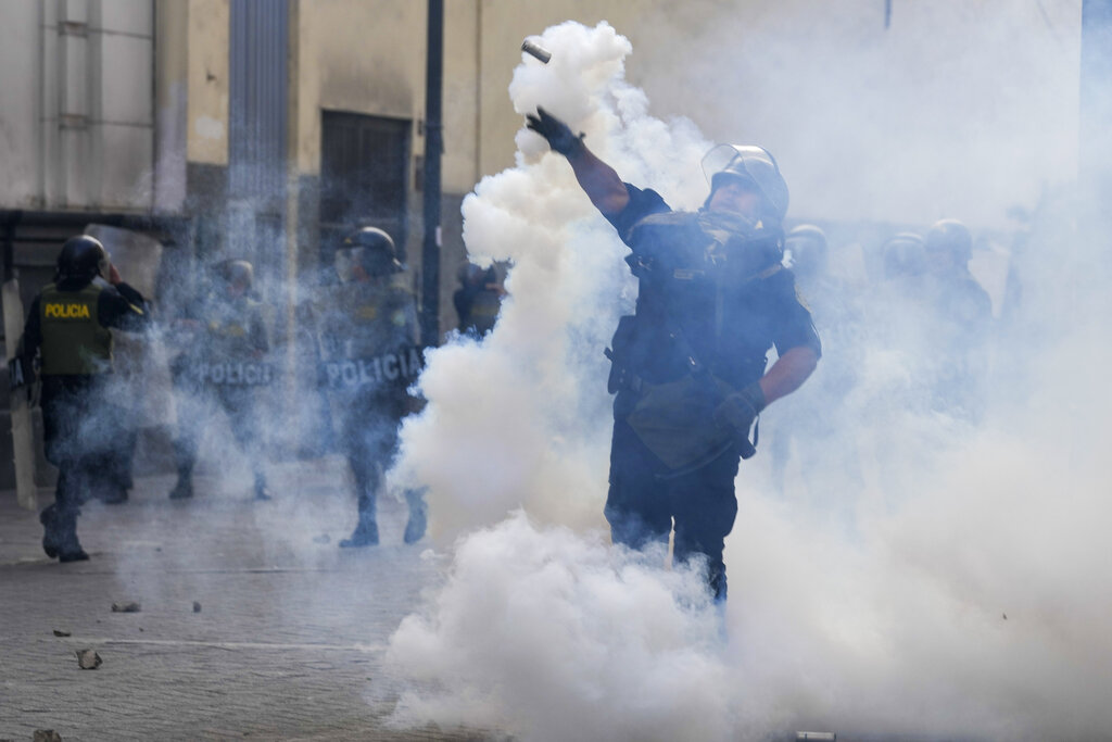 A police officer throws a tear gas canister at supporters of ousted President Pedro Castillo during a protest in Lima, Peru, Monday, Dec. 12, 2022. Peru's Congress voted to remove Castillo from office Wednesday and replace him with the vice president, shortly after Castillo tried to dissolve the legislature ahead of a scheduled vote to remove him. (AP Photo/Martin Mejia)
