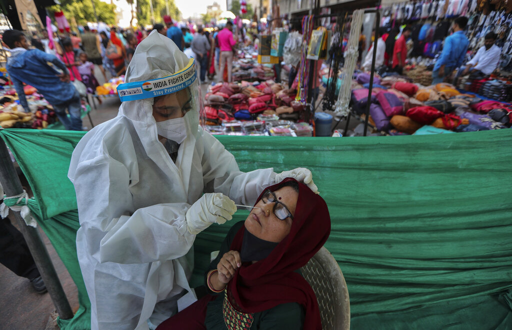 A health worker takes a nasal swab sample of a woman to test for COVID-19 at a facility erected in a market in Ahmedabad, India, Tuesday, Nov. 17, 2020. A country of nearly 1.4 billion people, India is the world's second most coronavirus affected country after the United States. (AP Photo/Ajit Solanki)