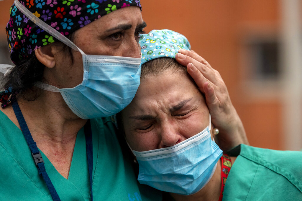 Health workers cry during a memorial for their co-worker Esteban, a nurse who died from COVID-19, at the Severo Ochoa Hospital in Leganes in Leganes, Spain, Friday, April 10, 2020. (AP Photo/Manu Fernandez)