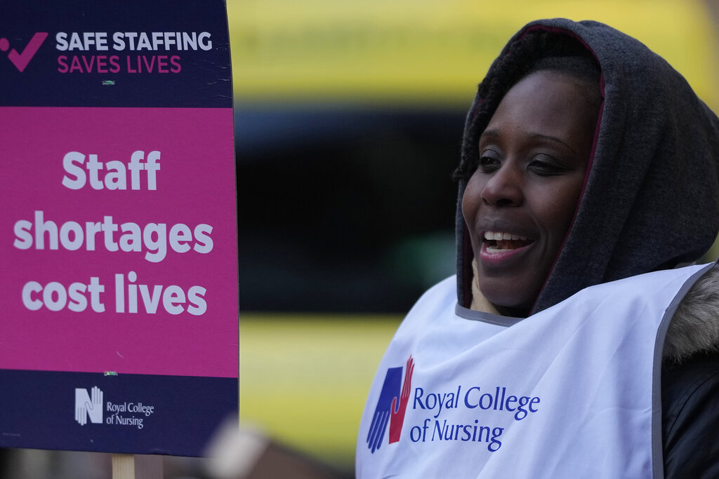 A nurse holds a placard on the picket line as she participates in a strike action over pay in London, Tuesday, Dec. 20, 2022. Nurses in England, Wales and Ireland will stage the biggest strike in the history of the Royal College of Nursing (RCN). Up to 100,000 members will walk out at 65 NHS (National Health Services) organisations. (AP Photo/Alastair Grant)