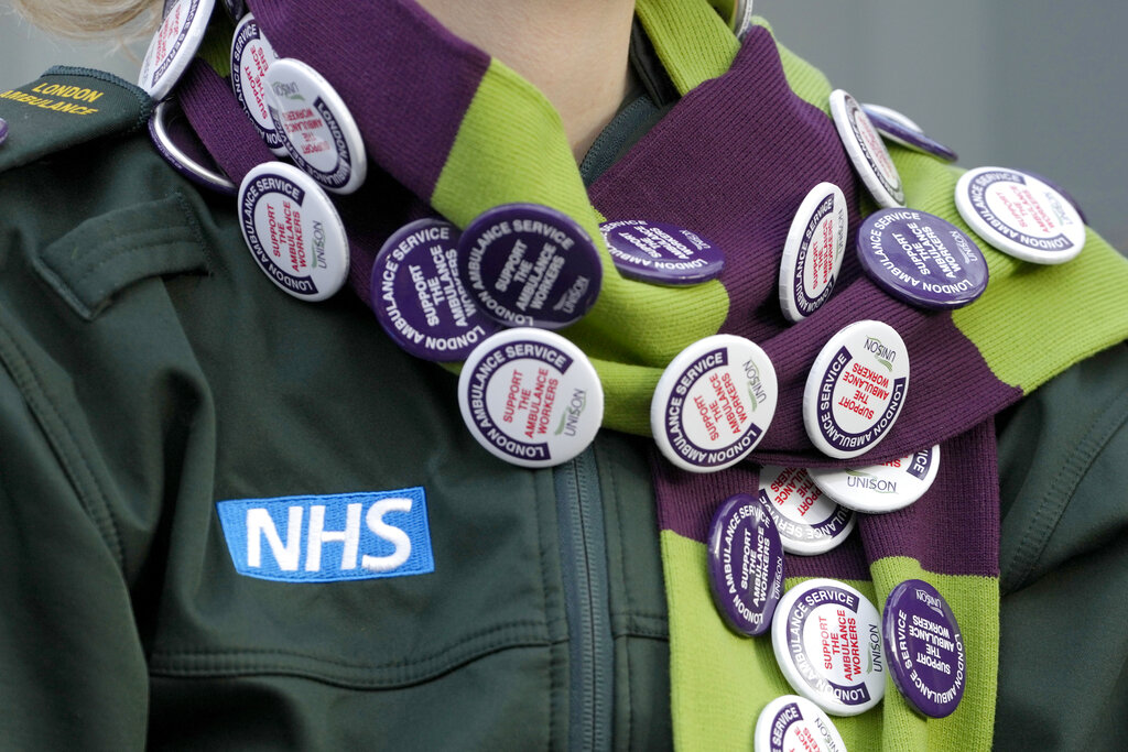 Badges are worn by an ambulance worker on a picket line in London, Wednesday, Dec. 21, 2022. Thousands of ambulance workers in Britain are staging a 24-hour strike, with unions and the government swapping accusations of blame for putting lives at risk. The government is telling people not to play contact sports, take unnecessary car trips or get drunk in order to reduce their risk of needing an ambulance on Wednesday. (AP Photo/Kirsty Wigglesworth)