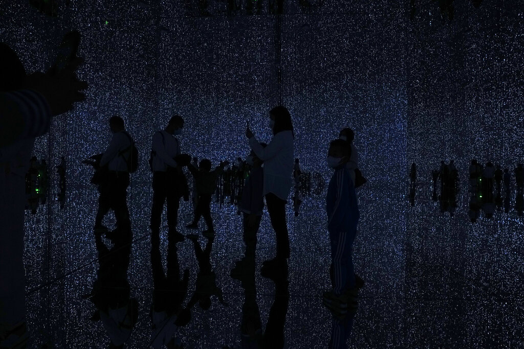 Visitors are silhouetted as they experience with immersive digital art installation titled 