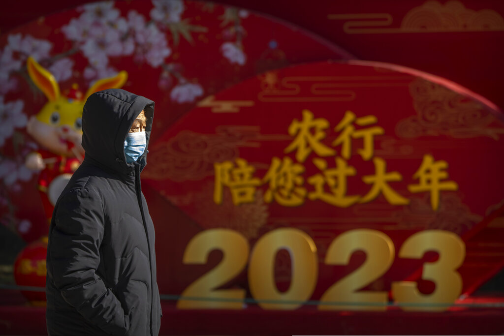 A man wearing a face mask walks past a display for the upcoming Lunar New Year at a public park in Beijing, Friday, Jan. 20, 2023. The Year of the Rabbit officially begins on Jan. 22. (AP Photo/Mark Schiefelbein)