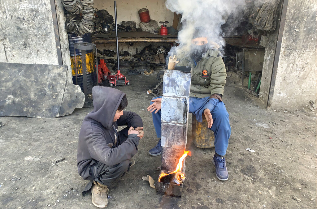 Afghan boys warm themselves near a fire in cold weather as they work helping a car mechanic in Kabul, Afghanistan, Tuesday, Dec. 29, 2020. (AP Photo/Rahmat Gul)