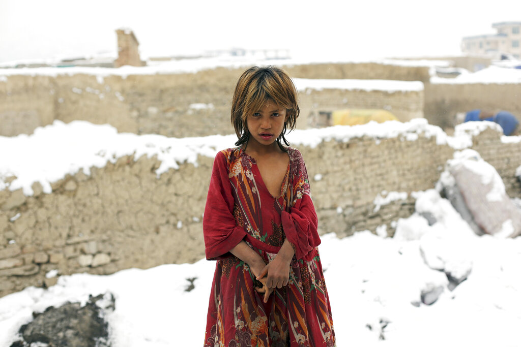 An internally displaced Afghan girl poses for a photograph at a camp in the snow on the outskirts of Kabul, Afghanistan, Sunday, Jan. 12, 2020. Kabul has been experiencing below freezing weather and snow. (AP Photo/Rahmat Gul)