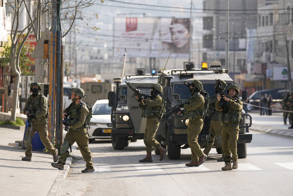 Israeli soldiers take up positions at the scene of a Palestinian shooting attack at the Hawara checkpoint, near the West Bank city of Nablus, Sunday, Feb. 26, 2023. (AP Photo/Majdi Mohammed)