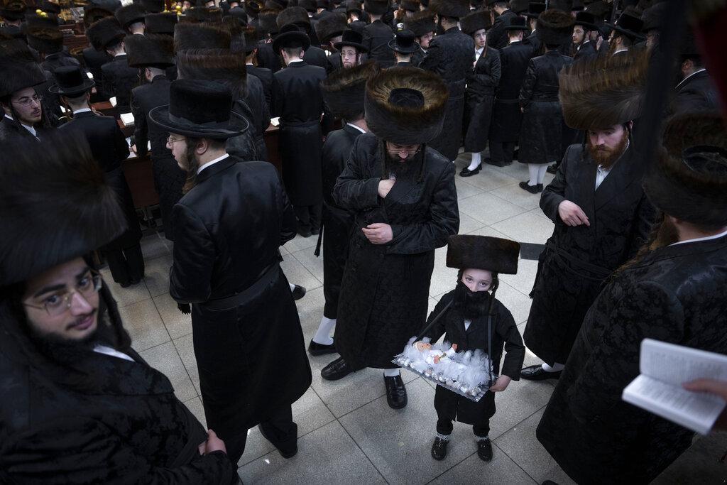 Jewish ultra-Orthodox men and children, some wearing costumes as they celebrate the Jewish festival of Purim at a synagogue in Bnei Brak, Israel, Monday, March 6, 2023. The Jewish holiday of Purim commemorates the Jews' salvation from genocide in ancient Persia, as recounted in the Book of Esther. (AP Photo/Oded Balilty)