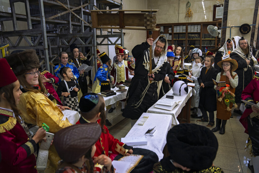 Jewish ultra-Orthodox men and children, some wearing costumes read the Book of Esther, which tells the story of the Jewish festival of Purim, at a synagogue in Bnei Brak, Israel, Thursday, March 17, 2022. The Jewish holiday of Purim commemorates the Jews' salvation from genocide in ancient Persia, as recounted in the Book of Esther. (AP Photo/Oded Balilty)