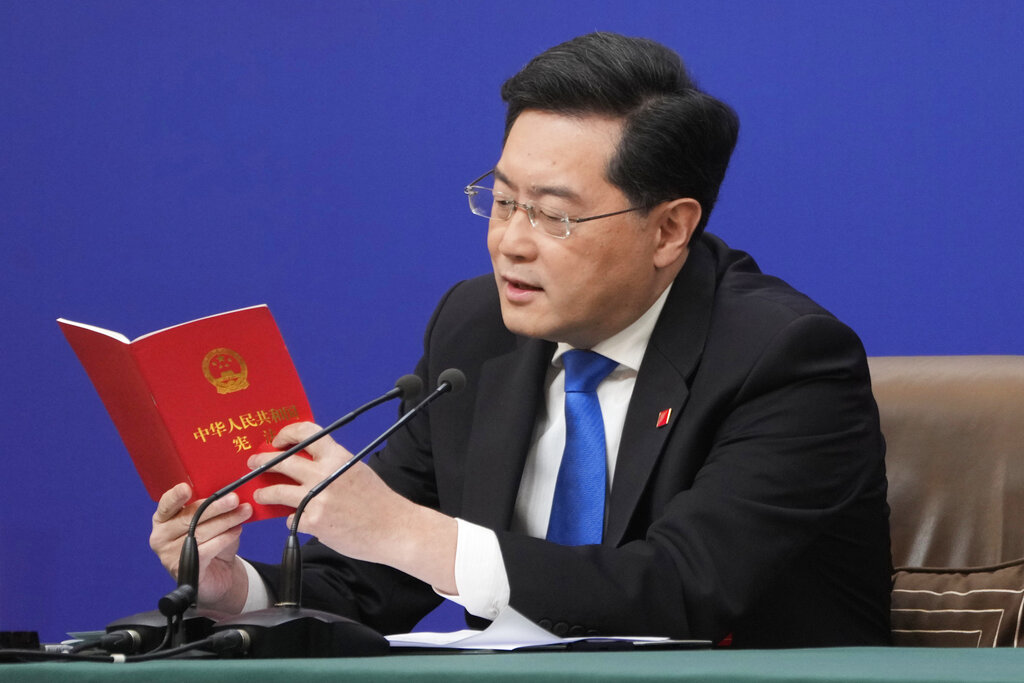 FILE - Chinese Foreign Minister Qin Gang reads from the Chinese constitution when answering a question about Taiwan during a news conference held on the sidelines of the annual meeting of China's National People's Congress (NPC) in Beijing, Tuesday, March 7, 2023. China's President Xi Jinping accused Washington Monday of trying to isolate his country and hold back its development. Xi also said a U.S.-led campaign of “containment and suppression” of China has “brought unprecedented, severe challenges.” He called on the public to “dare to fight.” Qin on Tuesday sharpened the warning, saying Washington faces possible “conflict and confrontation” if it fails to change course. (AP Photo/Mark Schiefelbein, File)