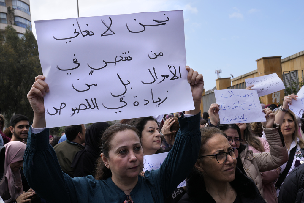 A teacher holds up an Arabic placard that reads: 
