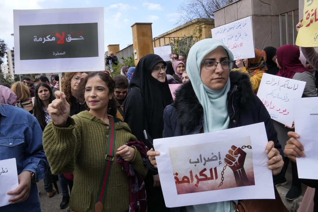 Lebanese teachers hold Arabic placards that read: 