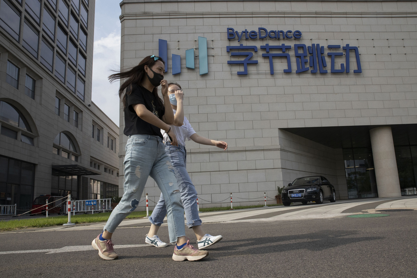 Women wearing masks to prevent the spread of the coronavirus chat as they pass by the ByteDance headquarters in Beijing, China on Friday, Aug. 7, 2020. President Donald Trump on Thursday ordered a sweeping but unspecified ban on dealings with the Chinese owners of consumer apps TikTok and WeChat, although it remains unclear if he has the legal authority to actually ban the apps from the U.S. TikTok is owned by Chinese company ByteDance. (AP Photo/Ng Han Guan)