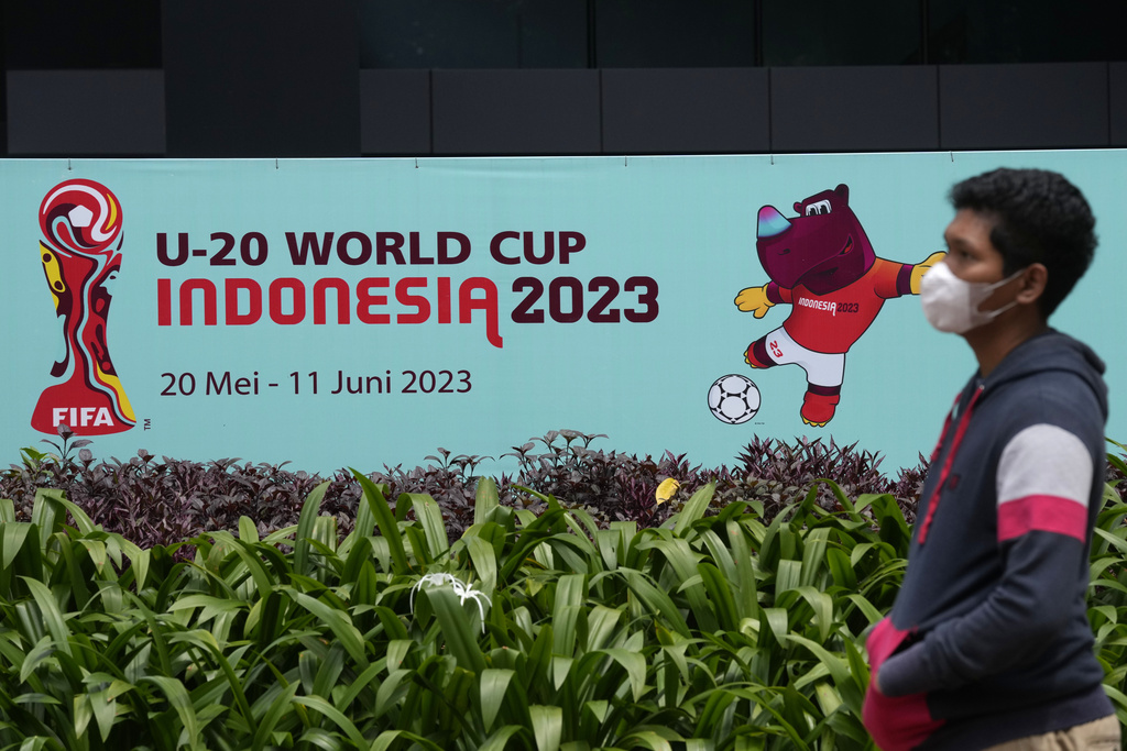 A man walks past a banner of FIFA U-20 World Cup outside the building housing the office of Indonesian Soccer Association, PSSI, in Jakarta, Indonesia, Thursday, March 30, 2023. Indonesia was stripped of hosting rights for the Under-20 World Cup on Wednesday only eight weeks before the start of the tournament amid political turmoil regarding Israel's participation. (AP Photo/Dita Alangkara)