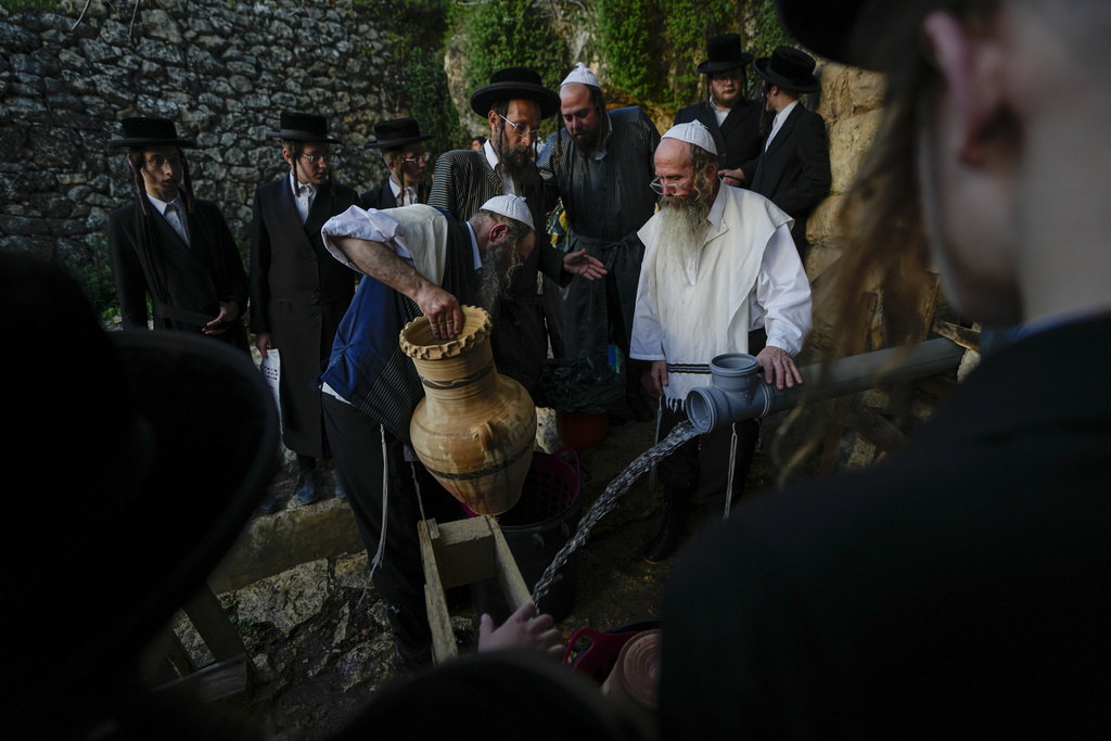 Ultra-Orthodox Jews collect water from a spring to make matzoh, a traditional handmade unleavened bread for Passover, during the Maim Shelanu ceremony at a mountain spring in the outskirts of Jerusalem, Tuesday, April 4, 2023. Jews are forbidden to eat leavened foodstuffs during the Passover holiday that celebrates the biblical story of the Israelites' escape from slavery and exodus from Egypt. (AP Photo/Ariel Schalit)