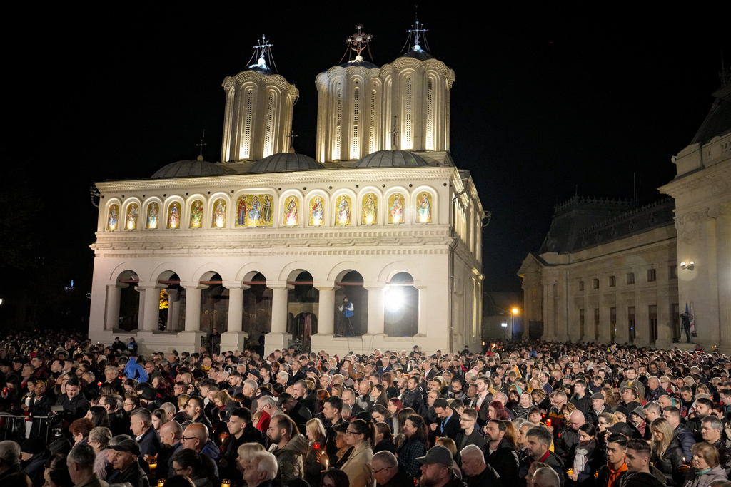 People wait to receive the holy light during the Orthodox Easter religious service at the Patriarchal Cathedral in Bucharest, Romania, early Sunday, April 16, 2023. (AP Photo/Andreea Alexandru)