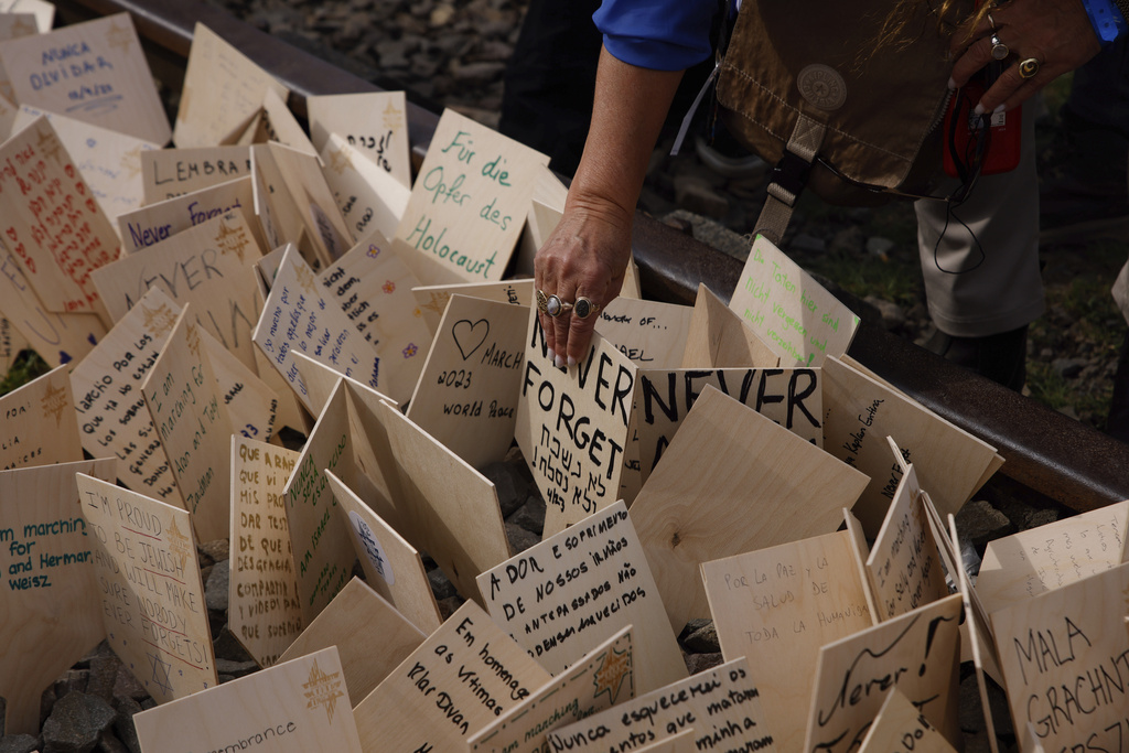 A woman places a wooden board with wishes during the annual 'March of the Living', a trek between two former Nazi-run death camps, in Oswiecim, Poland, Tuesday, April 18, 2023 to mourn victims of the Holocaust and celebrate the existence of the Jewish state. (AP Photo/Michal Dyjuk)