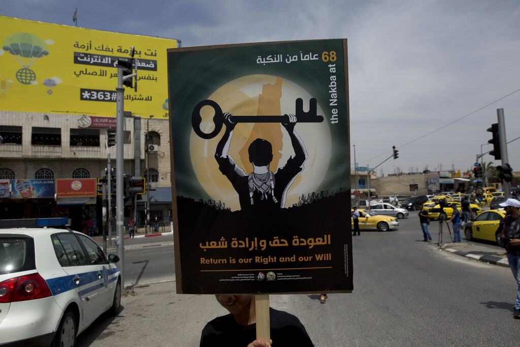 A Palestinian refugee carries a poster while marking 