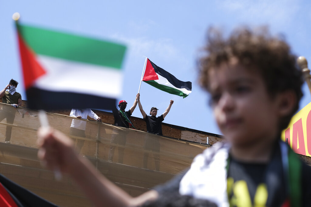 Demonstrators holding flags stand on the top of a building during a protest outside Israeli Consulate against Israel and in support of Palestinians, and marking the 73rd anniversary of what the Palestinians call the 