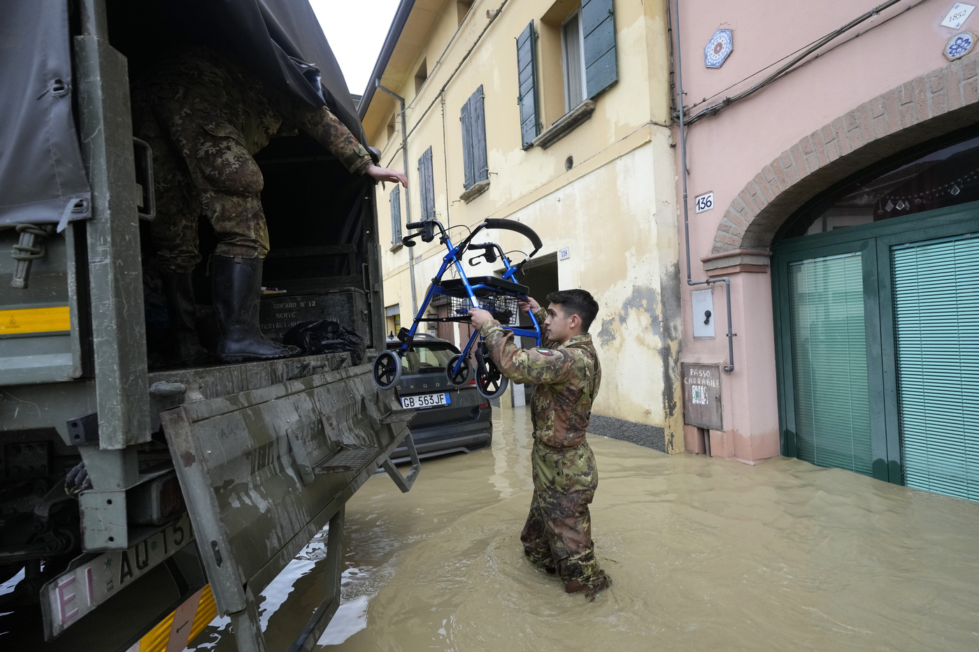 A soldier carries a walker in the flooded village of Castel Bolognese, Italy, Wednesday, May 17, 2023. Exceptional rains Wednesday in a drought-struck region of northern Italy swelled rivers over their banks, killing at least eight people, forcing the evacuation of thousands and prompting officials to warn that Italy needs a national plan to combat climate change-induced flooding. (AP Photo/Luca Bruno)