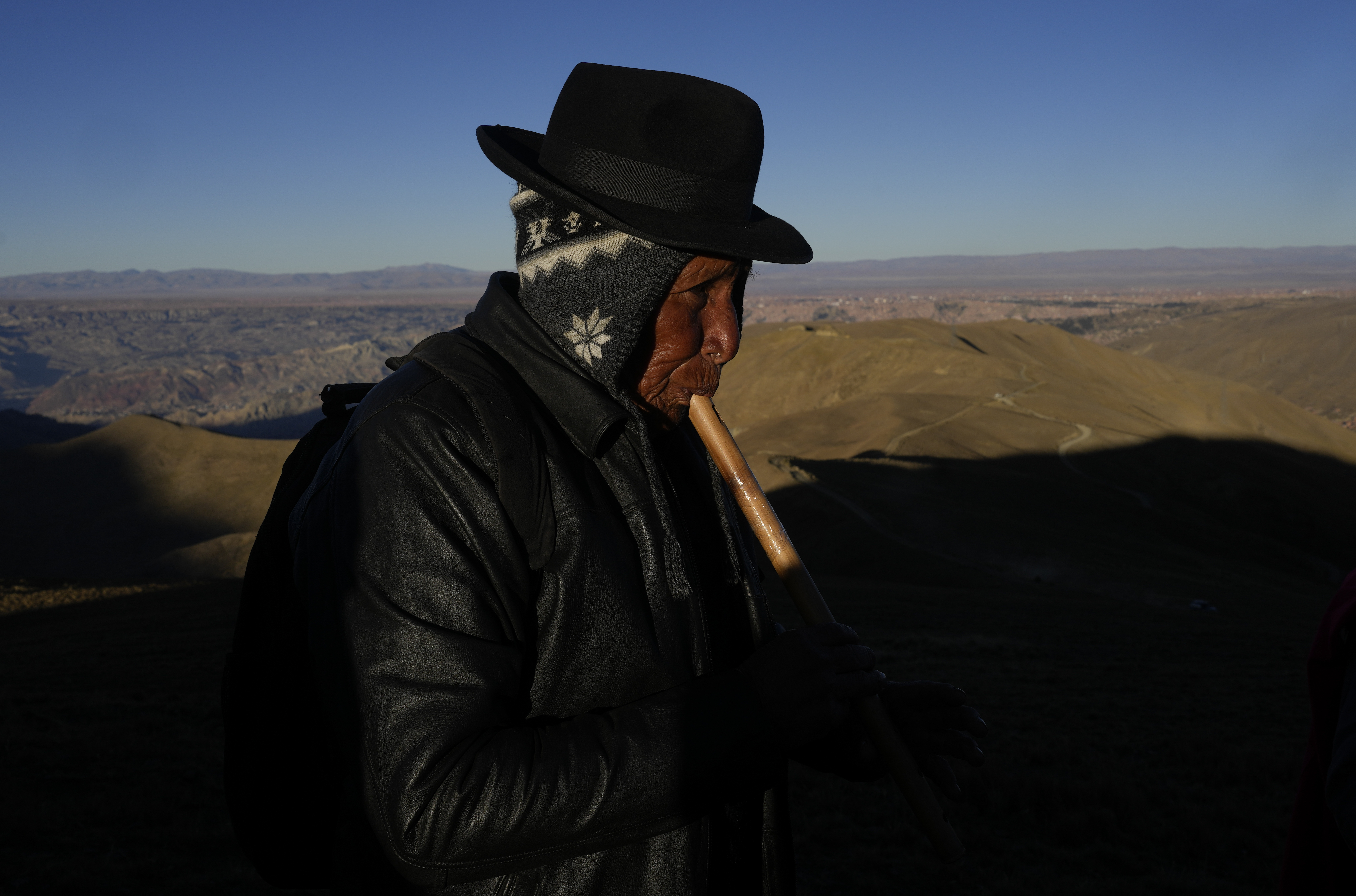 An Indigenous plays plays his Andean flute after receiving the first rays of sunlight in a New Year's ritual on the sacred mountain Apacheta Murmutani on the outskirts of Hampaturi, Bolivia, early Wednesday, June 21, 2023. Aymara Indigenous communities are celebrating the Andean new year 5,531 or 