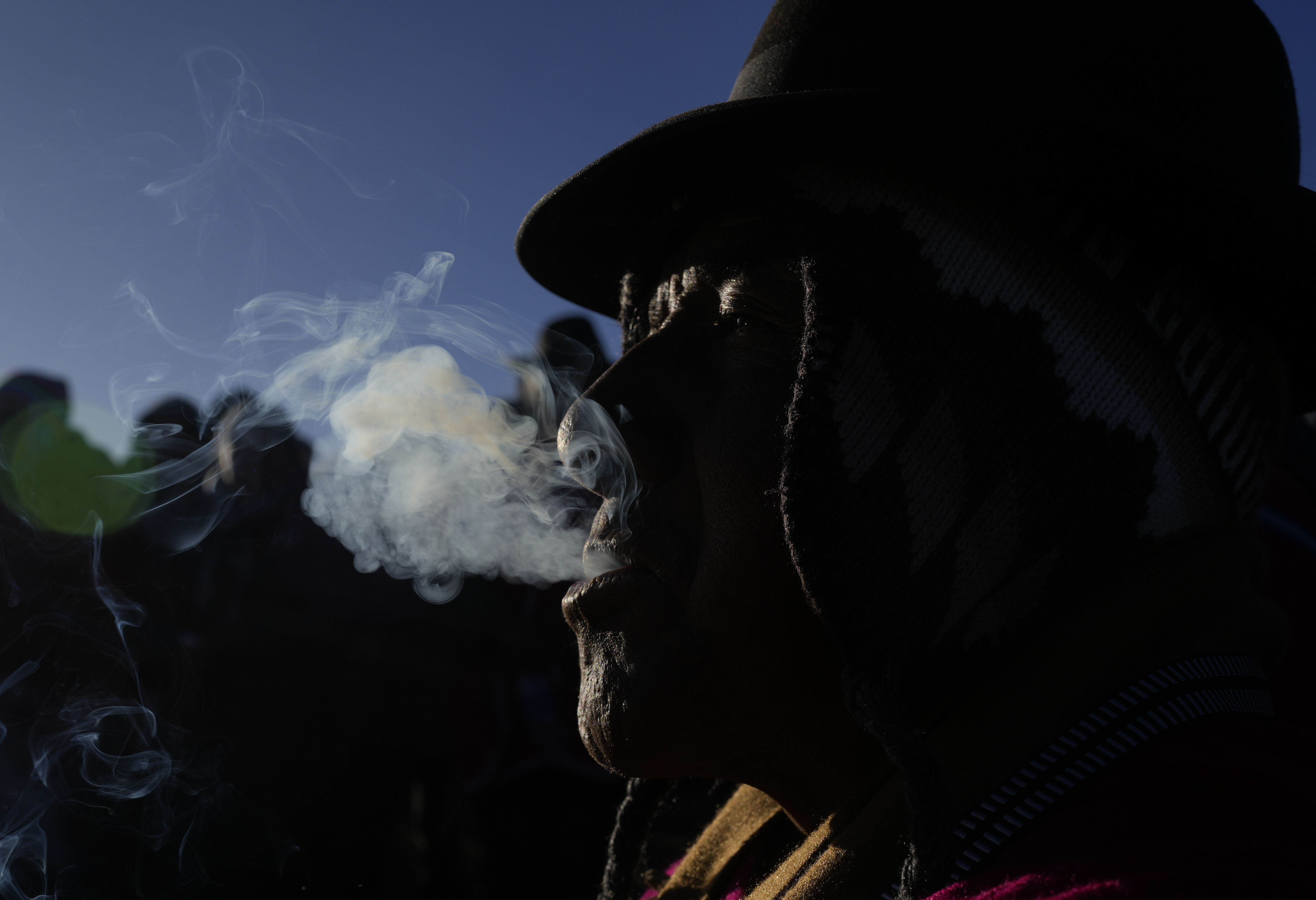 An Aymara men exhales smoke during a New Year's ritual on the sacred mountain Apacheta Murmutani on the outskirts of Hampaturi, Bolivia, early Wednesday, June 21, 2023. Aymara Indigenous communities are celebrating the Andean new year 5,531 or 
