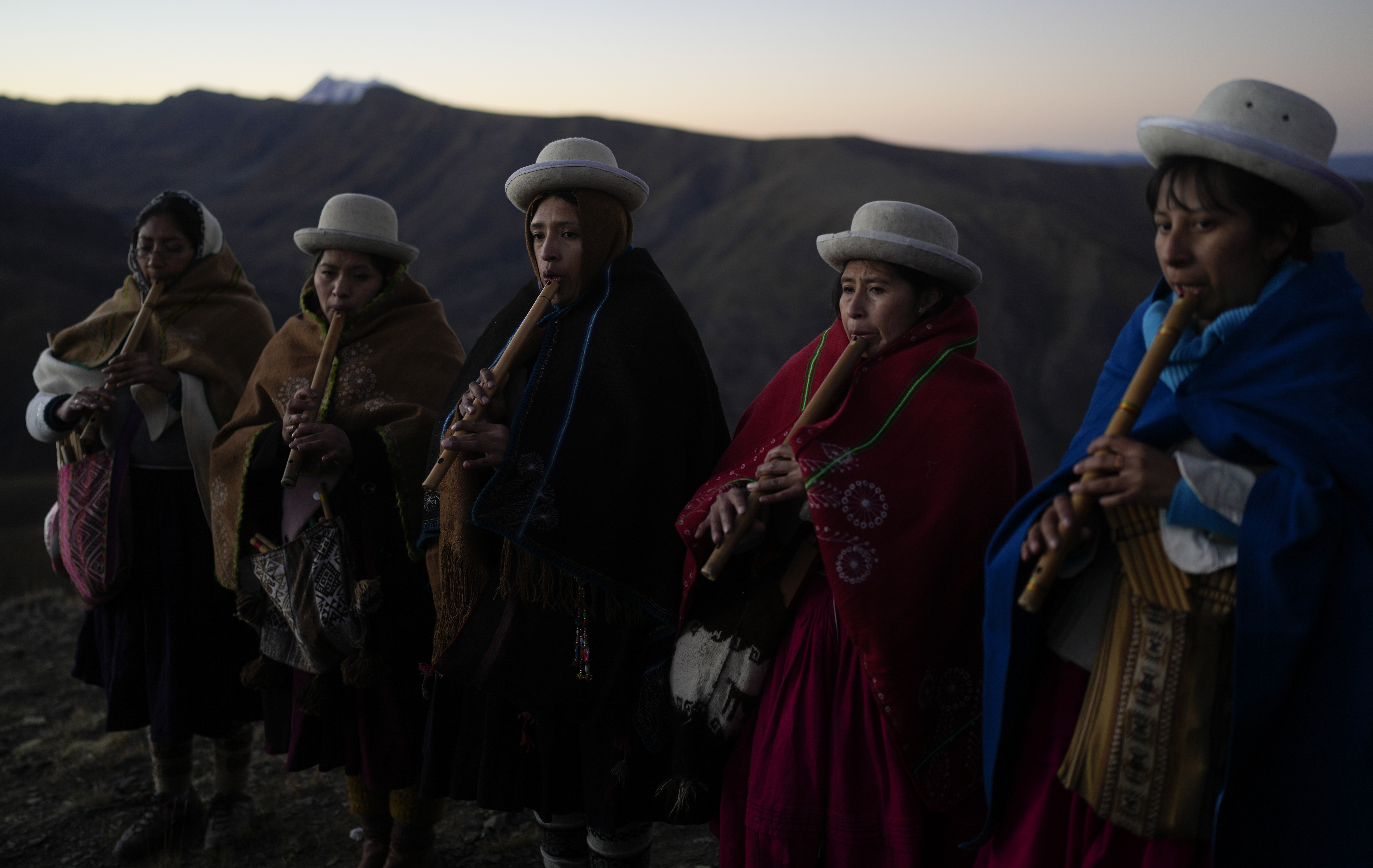 Musicians perform before as they wait for the first rays of sunlight in a New Year's ritual on the sacred mountain Apacheta Murmutani on the outskirts of Hampaturi, Bolivia, early Wednesday, June 21, 2023. Aymara Indigenous communities are celebrating the Andean new year 5,531 or 