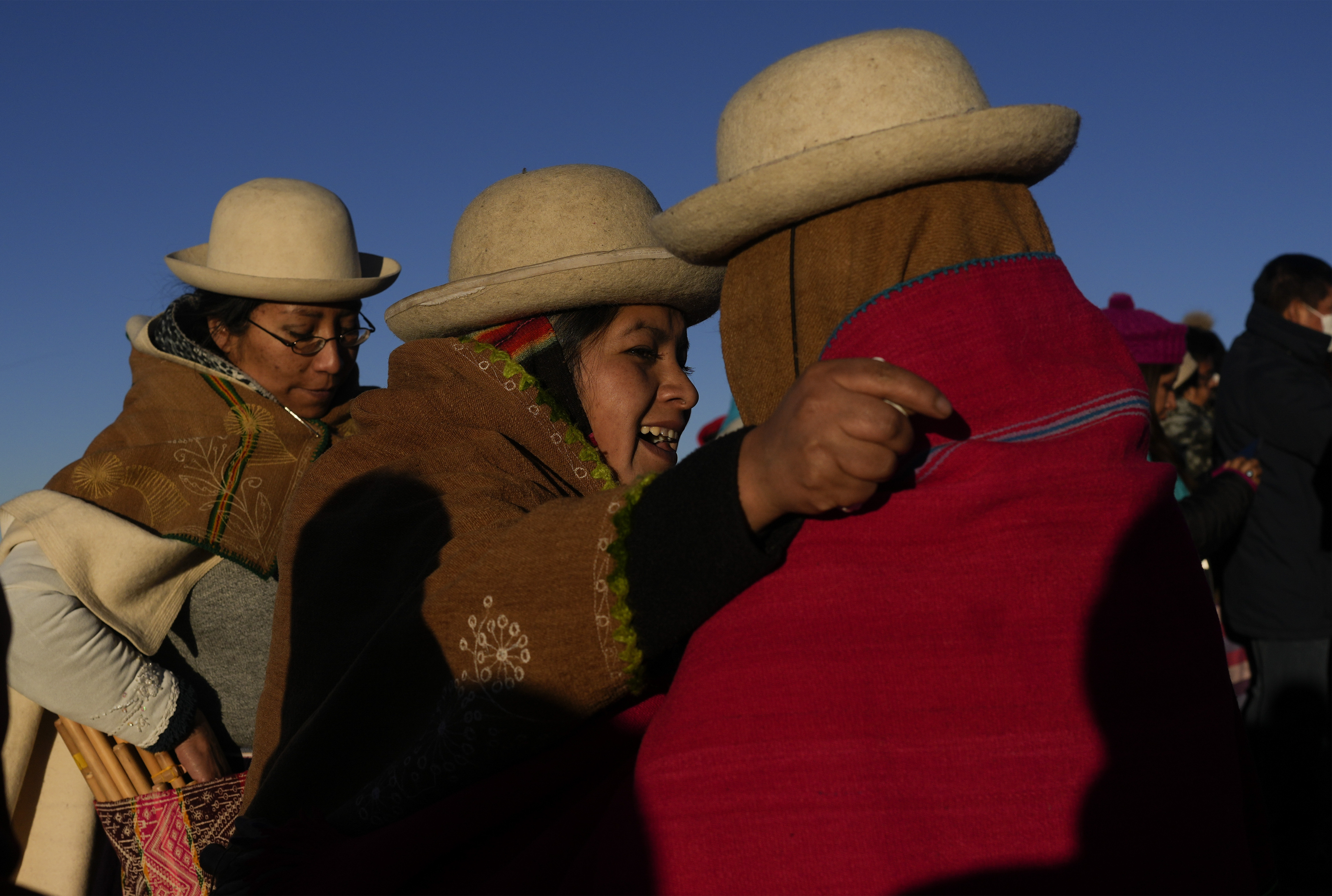 Aymara women embrace after receiving the first rays of sunlight in a New Year's ritual on the sacred mountain Apacheta Murmutani on the outskirts of Hampaturi, Bolivia, early Wednesday, June 21, 2023. Aymara Indigenous communities are celebrating the Andean new year 5,531 or 