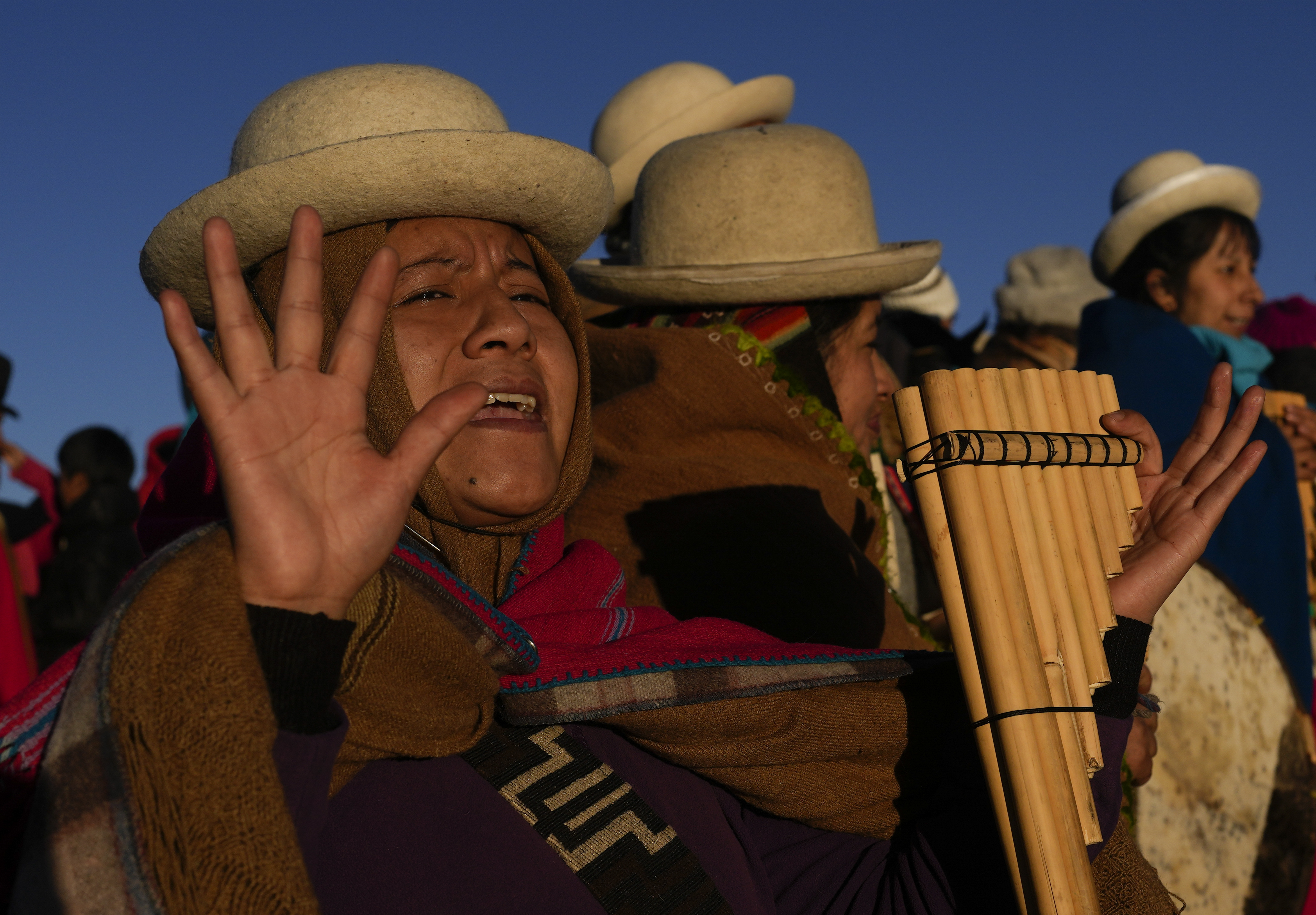 An Aymara Indigenous woman receives the first rays of sunlight in a New Year's ritual on the sacred mountain Apacheta Murmutani on the outskirts of Hampaturi, Bolivia, early Wednesday, June 21, 2023. Aymara Indigenous communities are celebrating the Andean new year 5,531 or 
