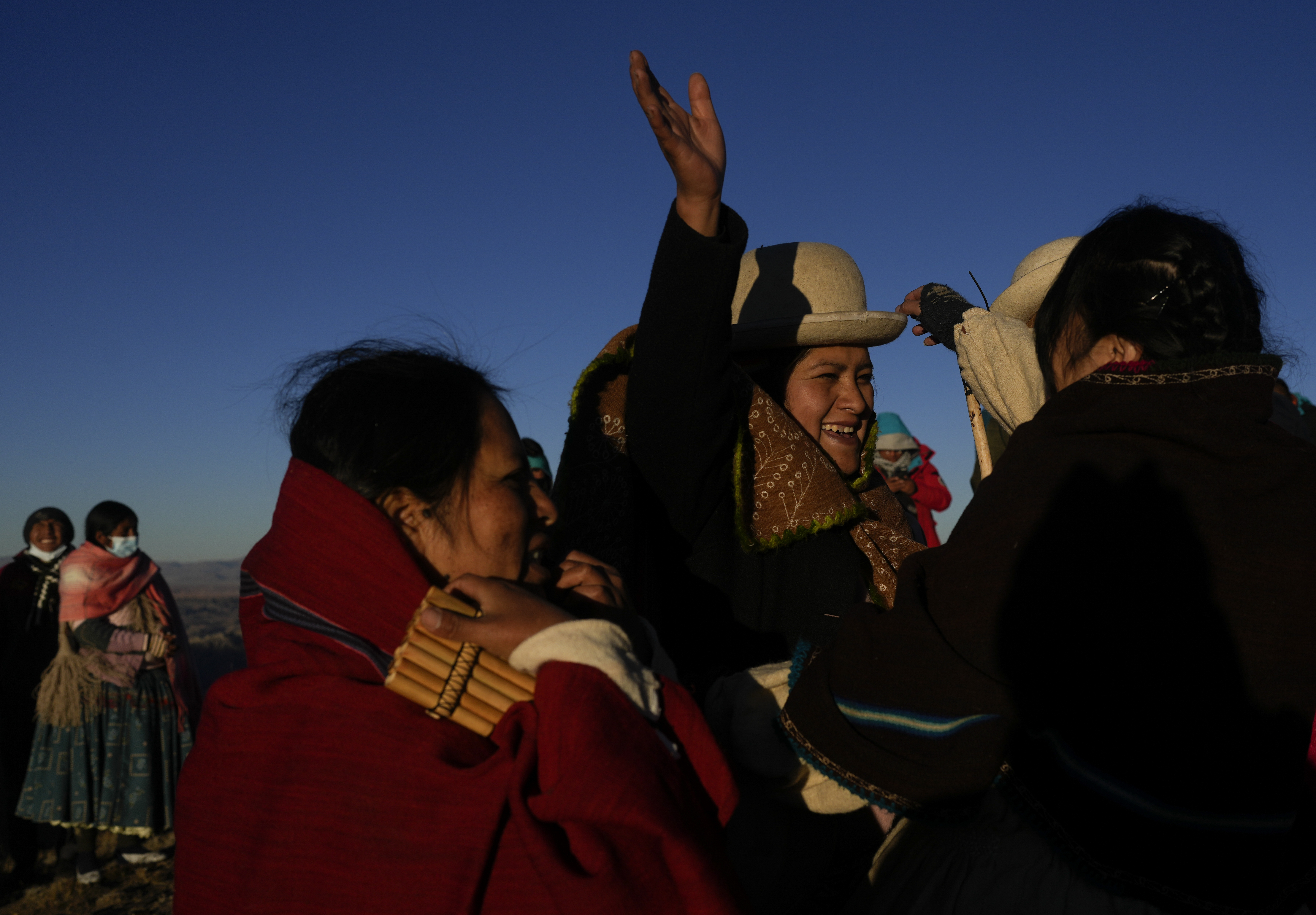 Aymara women embrace after receiving the first rays of sunlight in a New Year's ritual on the sacred mountain Apacheta Murmutani on the outskirts of Hampaturi, Bolivia, early Wednesday, June 21, 2023. Aymara Indigenous communities are celebrating the Andean new year 5,531 or 