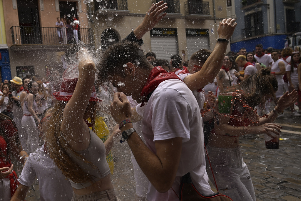 Revellers cool off with water thrown from balconies during the 'Chupinazo' rocket, which marks the official opening of the 2023 San Fermín fiestas in Pamplona, northern Spain, Thursday, July 6, 2023. (AP Photo/Alvaro Barrientos)