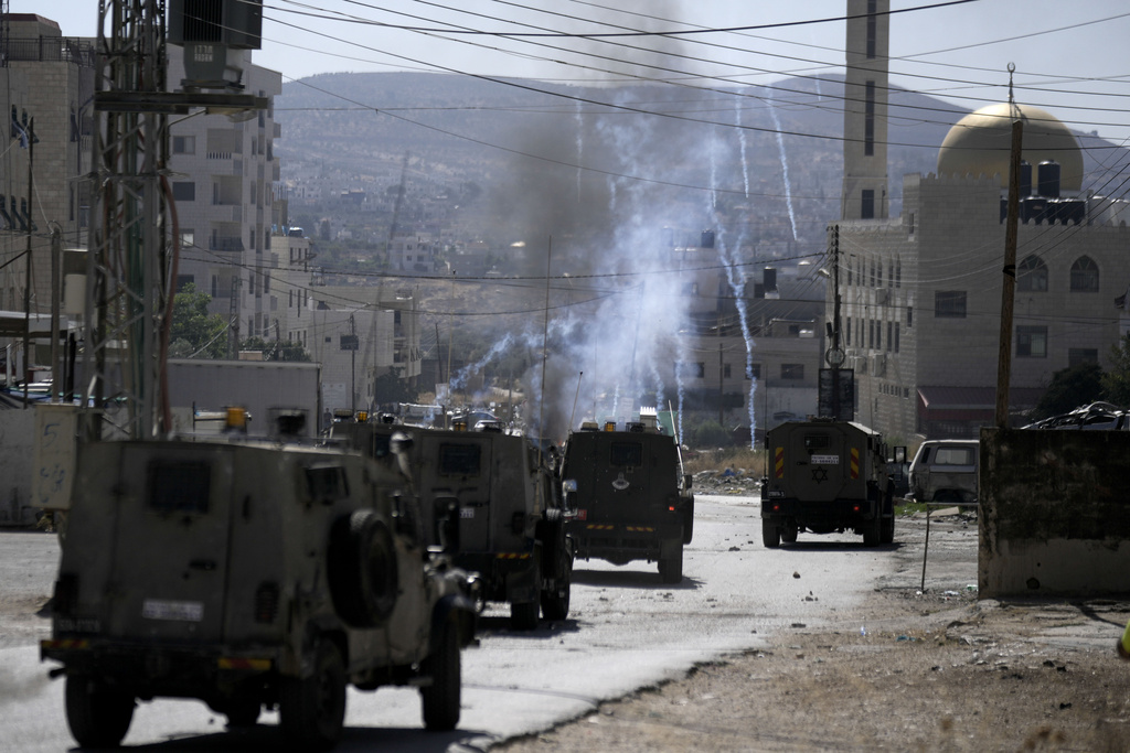 An Israeli military vehicle fires tear gas towards Palestinian protesters during a military raid in the Askar refugee camp the West Bank city of Nablus, on Monday, July 24, 2023. Israeli forces stormed into the Askar refugee camp near the northern West Bank city of Nablus on Monday, triggering clashes with Palestinian militants who opened fire and threw stones. At least a few Palestinians were wounded by live fire. (AP Photo/Majdi Mohammed).