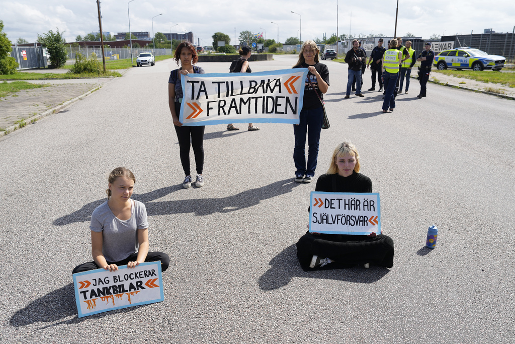 Greta Thunberg, left, and other activists block the entrance to an oil facility in Malmo, Sweden, Monday, July 24, 2023. The protest took place just a few hours after Thunberg was fined for disobeying police during a similar protest last month at the same terminal. (AP Photo/Pavel Golovkin)