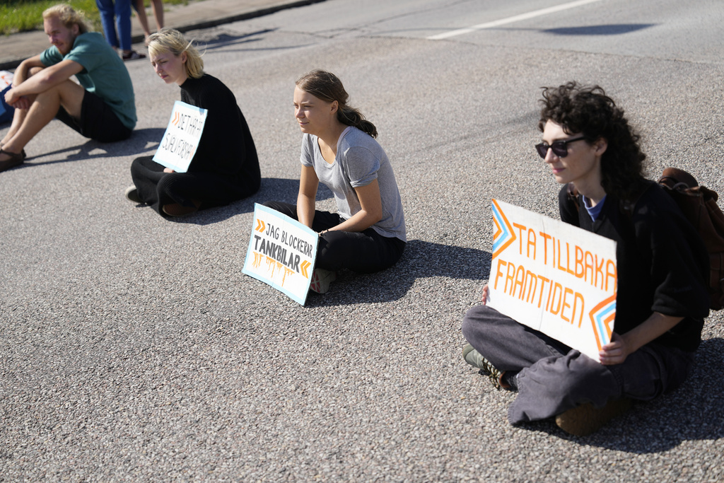 Greta Thunberg, centre, and other activists block the entrance to an oil facility in Malmo, Sweden, Monday, July 24, 2023. The protest took place just a few hours after Thunberg was fined for disobeying police during a similar protest last month at the same terminal. (AP Photo/Pavel Golovkin)