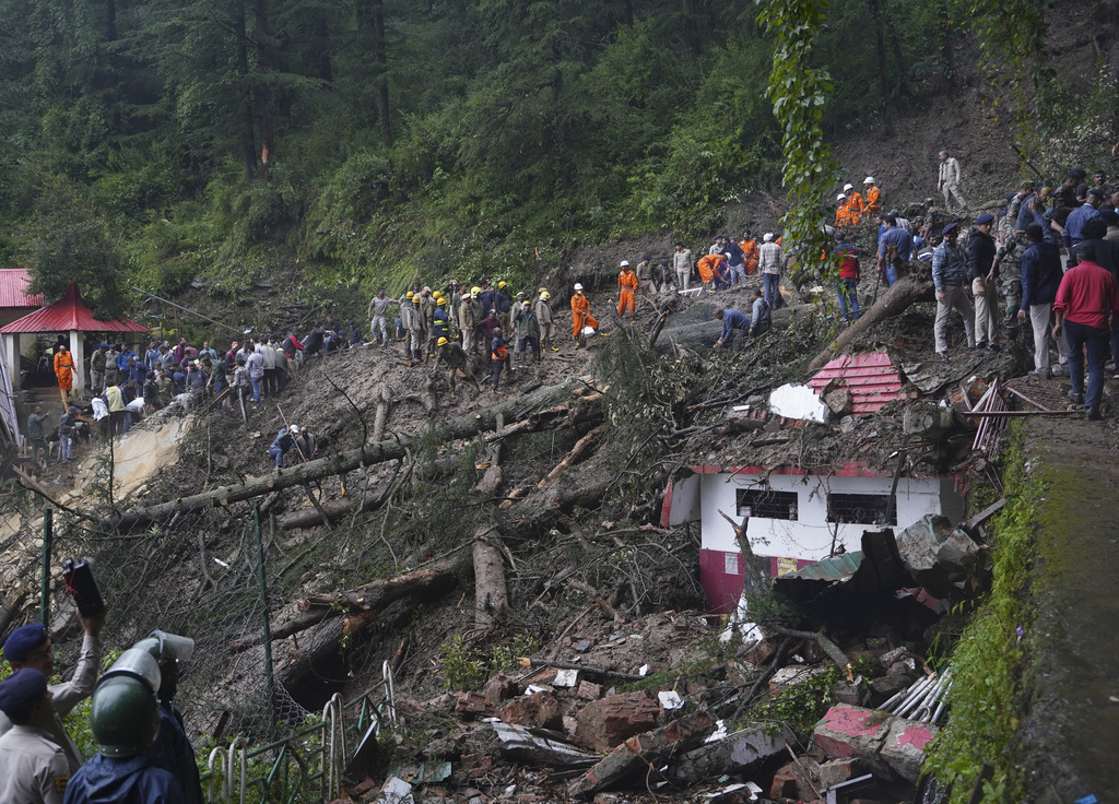 Rescuers remove mud and debris as they search for people feared trapped after a landslide near a temple on the outskirts of Shimla, Himachal Pradesh state, Monday, Aug.14, 2023. Heavy monsoon rains triggered floods and landslides in India's Himalayan region, leaving more than a dozen people dead and many others trapped, officials said Monday. (AP Photo/ Pradeep Kumar)
