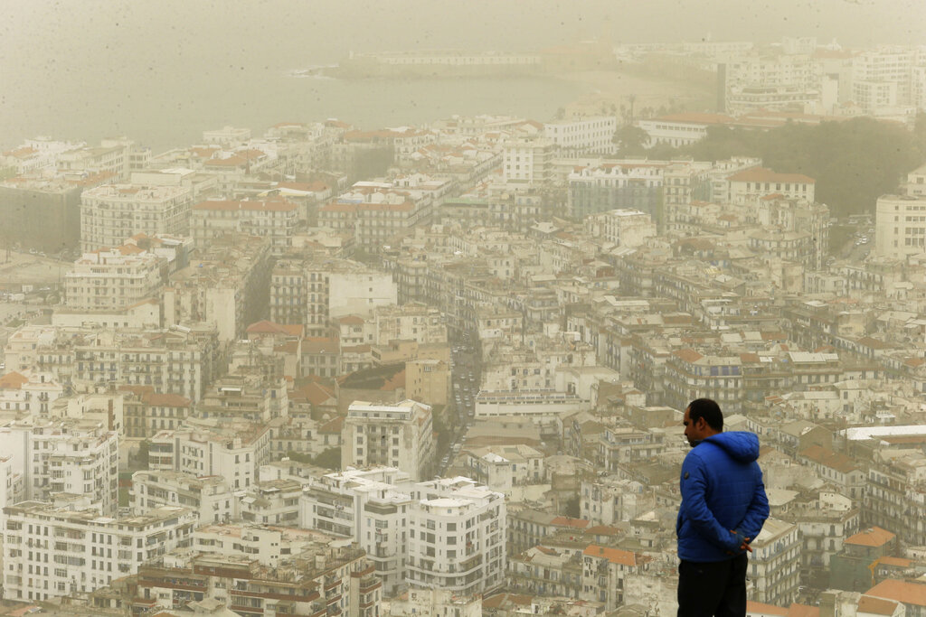 A man watches a cloud of sand dust from the Sahara desert flying over Algiers, Sunday, Feb.21, 2021. Recently, the Saharan dust plume, which covers parts of Southern and Central Europe, has caused short, rapid spikes in air pollution throughout the region. (AP Photo/Fateh Guidoum)