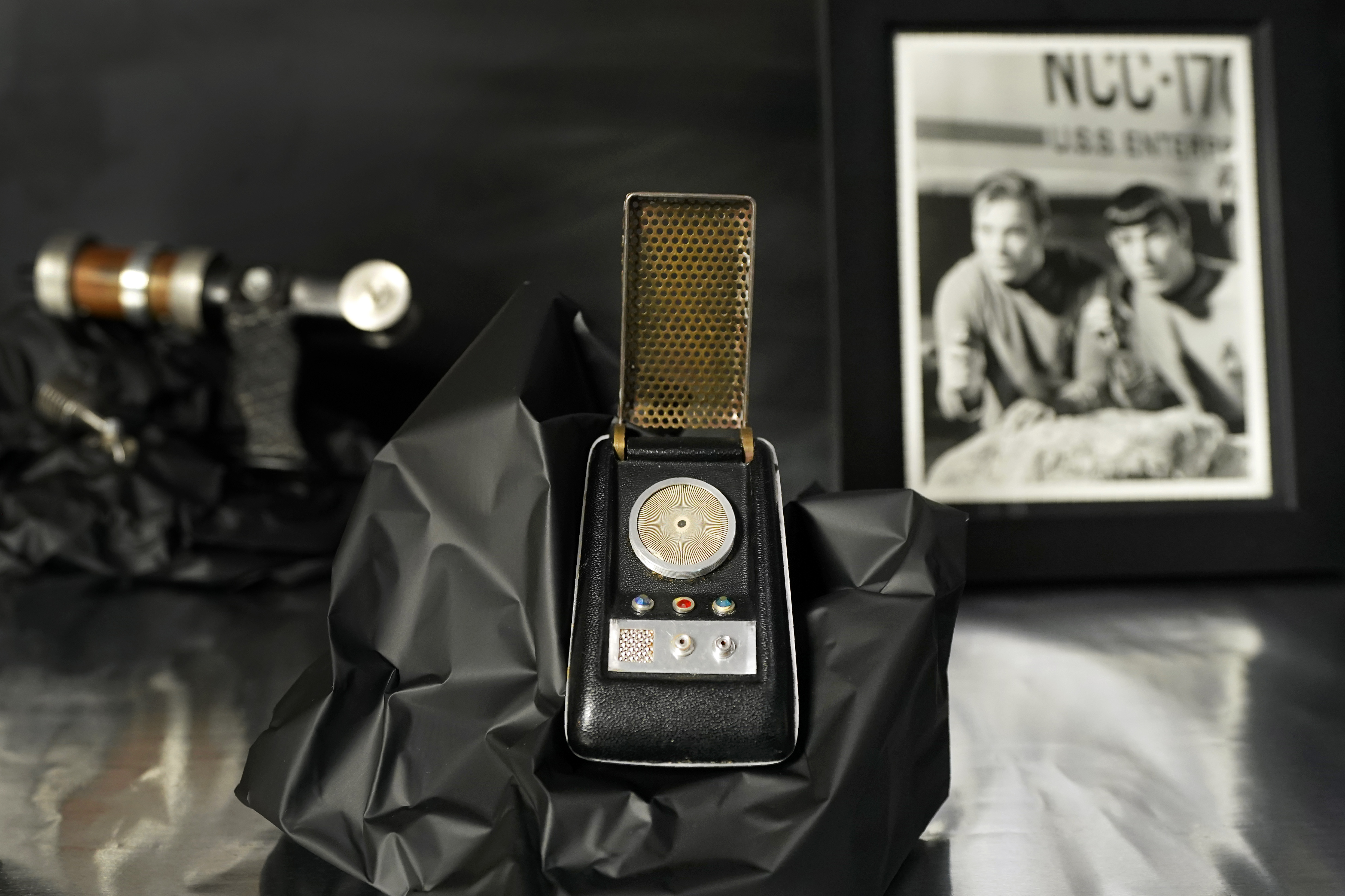 A prop called a Starfleet communicator, center, sits on display at Heritage Auctions, amongst others items from the 1960's television series, Thursday, Aug. 30, 2023, in Irving, Texas. While Greg Jein's work over nearly half a century making miniature models in Hollywood included such iconic creations as the alien mothership in 