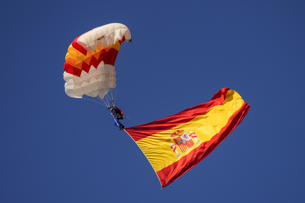 A paratrooper carries a Spanish flag during the military parade on the national holiday known as 