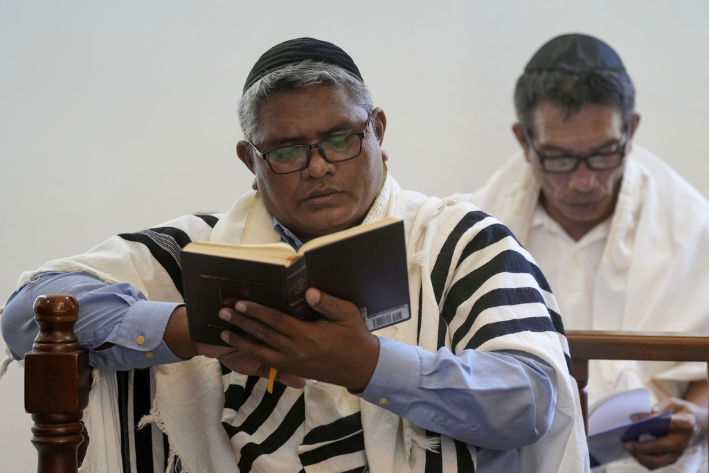 Modechai Ben Avraham, left, reads a book of prayer at Shaar Hashamayim Synagogue in Tondano, North Sulawesi, Indonesia, Saturday, Oct. 14, 2023. An Indonesian rabbi at the only synagogue in the world's most populous Muslim-majority nation, called on Saturday for peace and an an end to the fightings in Israel and Gaza. (AP Photo/Tatan Syuflana)