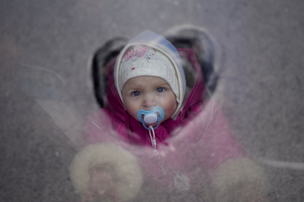 Una bambina ucraina in fuga dalla guerra, su un bus per la Polonia, foto Ap.